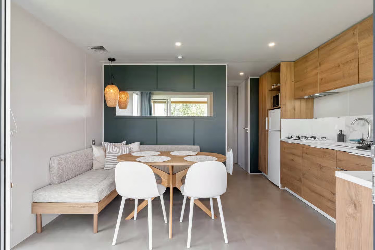 Séjour avec banquette d'angle, table ronde et cuisine ouverte
