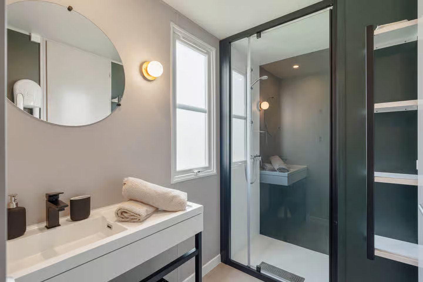 Salle de bain avec vasque, miroir rond et douche